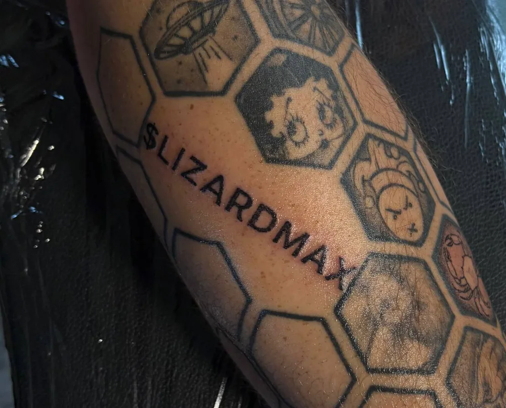 The $LIZARDMAX tattoo on Rob's forearm, inside a honeycomb of hexagons